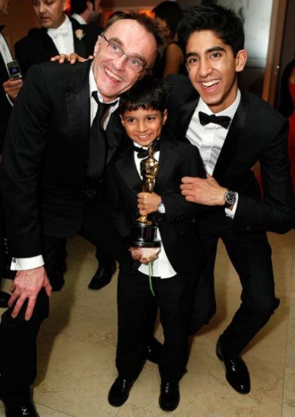 Director Danny Boyle, Ayush Mahesh Khedekar, and Dev Patel celebrate Slumdog Millionaire’s many awards. By